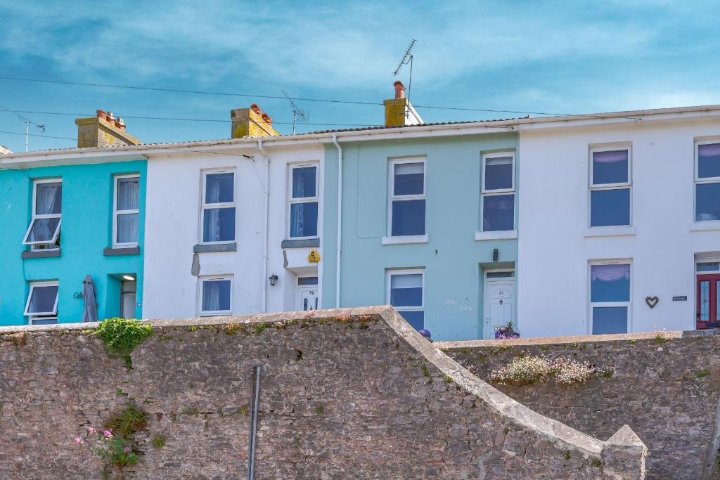 uma fila de casas coloridas atrás de uma parede em Bay View em Brixham