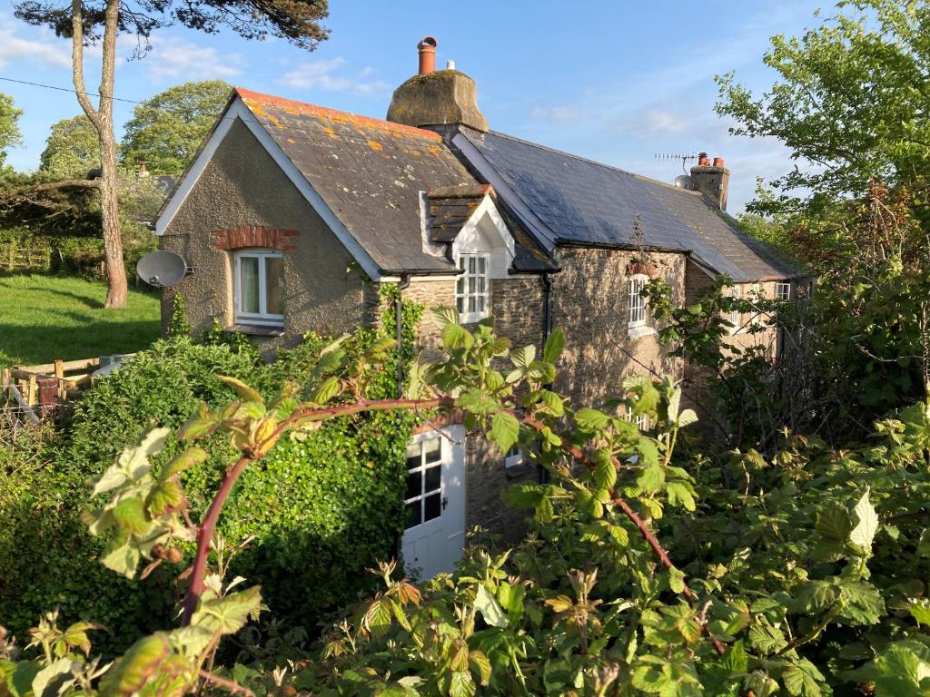 an old stone house in the middle of a garden at Yew Tree Cottage in Dartmouth