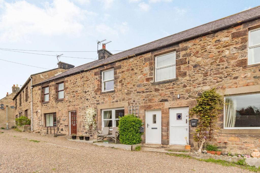 an old stone house with white doors and windows at Peth Head Cottage in Wooler