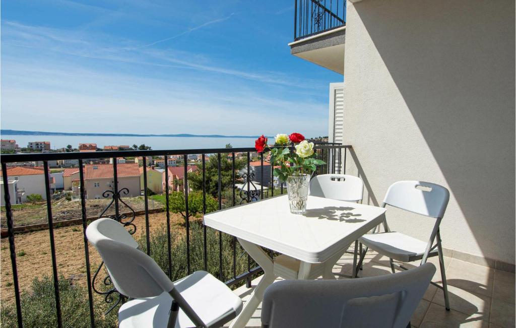 uma varanda com uma mesa e cadeiras brancas e o oceano em Amazing Apartment In Podstrana With Wifi em Podstrana