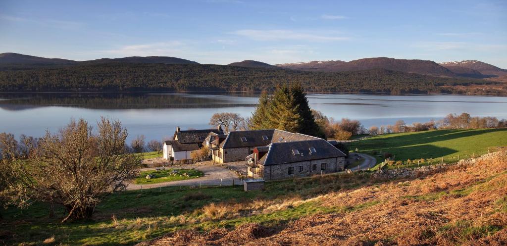 a house on a hill next to a lake at Stewart in Pitlochry