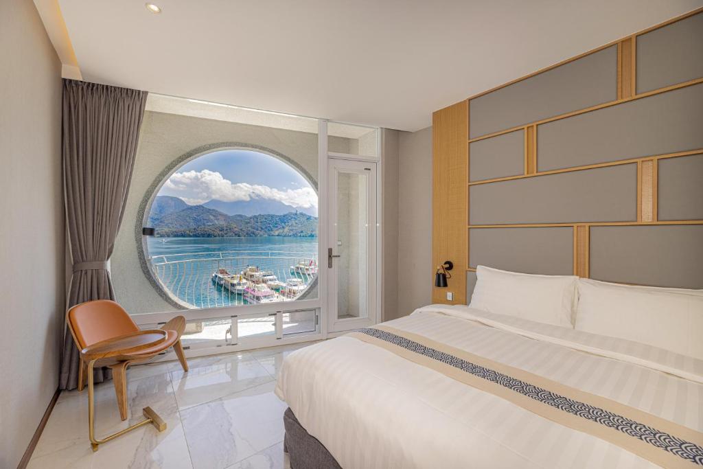 ein Schlafzimmer mit einem großen Bett und einem großen Fenster in der Unterkunft Sun Moon Lake Apollo Resort Hotel in Yuchi
