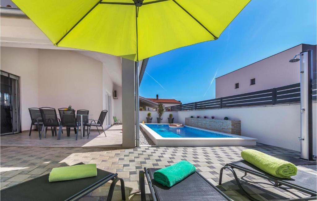 a patio with an umbrella and a swimming pool at Beautiful Home In Skatari With Outdoor Swimming Pool in Škatari
