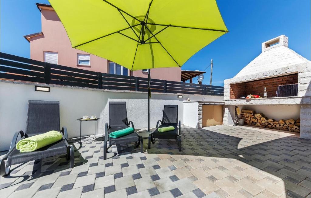 a patio with a yellow umbrella and chairs and a table at Beautiful Home In Skatari With Outdoor Swimming Pool in Škatari