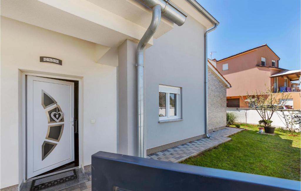 a white house with a door and a yard at Beautiful Home In Skatari With Outdoor Swimming Pool in Škatari