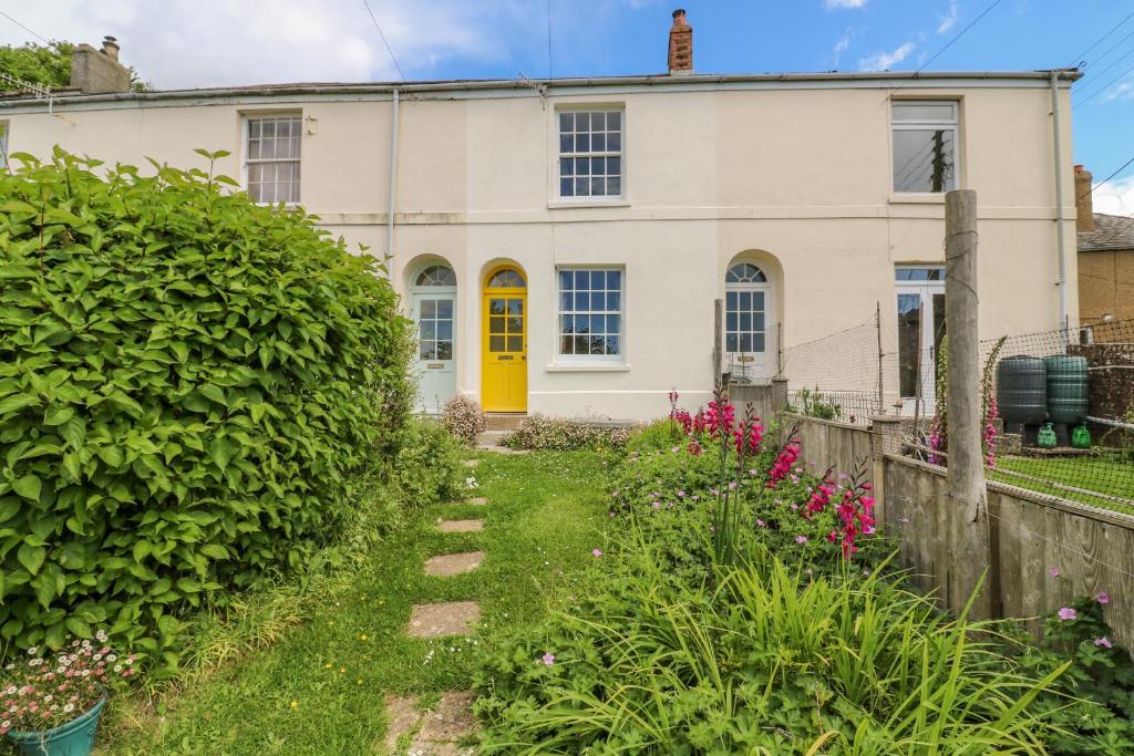 a house with a yellow door and a fence at Bedford Terrace in Bridport