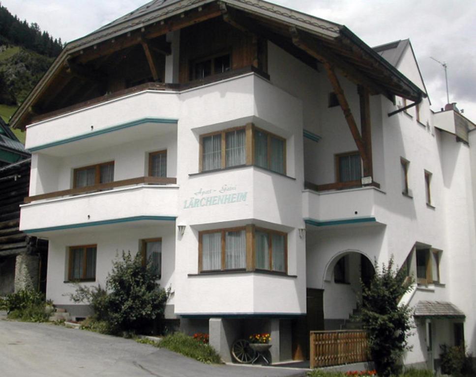 a white building with a wooden roof at Lärchenheim Apartments in Ischgl