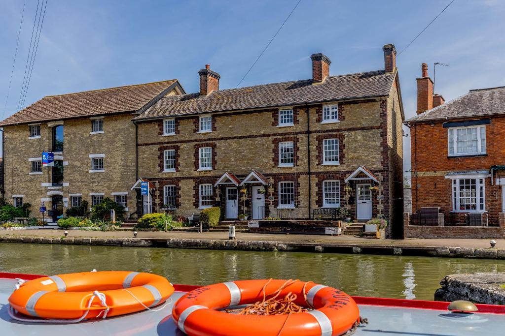two orange lifeboats on a boat in front of a building at 3 Canalside Cottages in Towcester