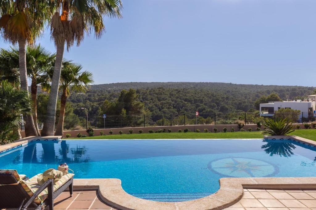 una gran piscina con palmeras en el fondo en Luxurious villa Sol de Mallorca, en Sol de Mallorca