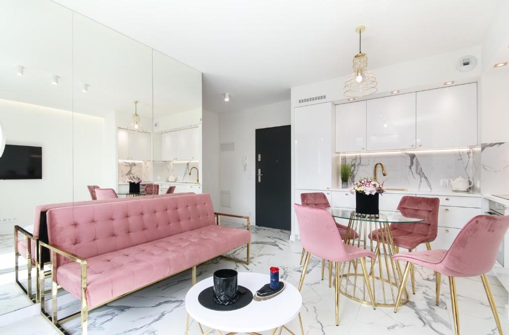 a living room with a pink couch and pink chairs at Apartamenty HashtagWilda_Apartament Złoty in Poznań