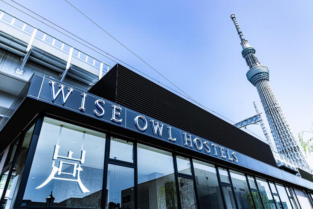 a building with a sign on it with a tower in the background at Wise Owl Hostels River Tokyo in Tokyo