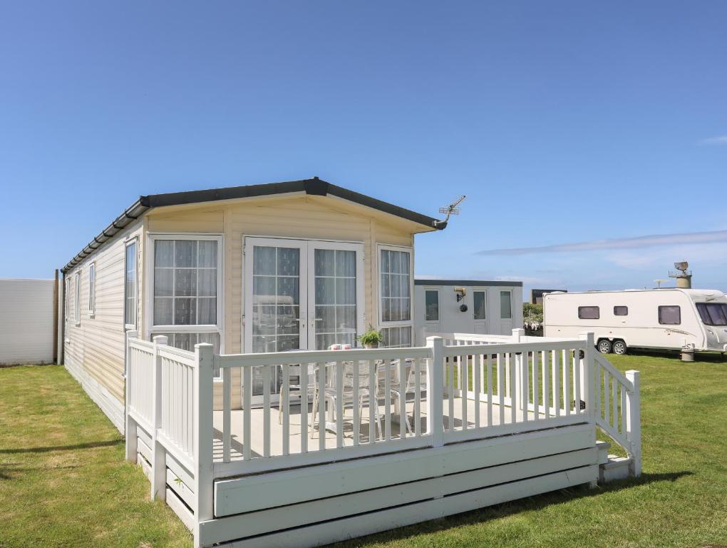 a tiny house with a white fence on a yard at Trewan Lodge in Holyhead