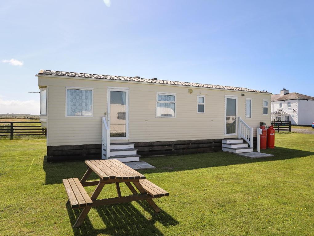 a tiny house with a picnic table in the yard at Trewan Chalet in Holyhead