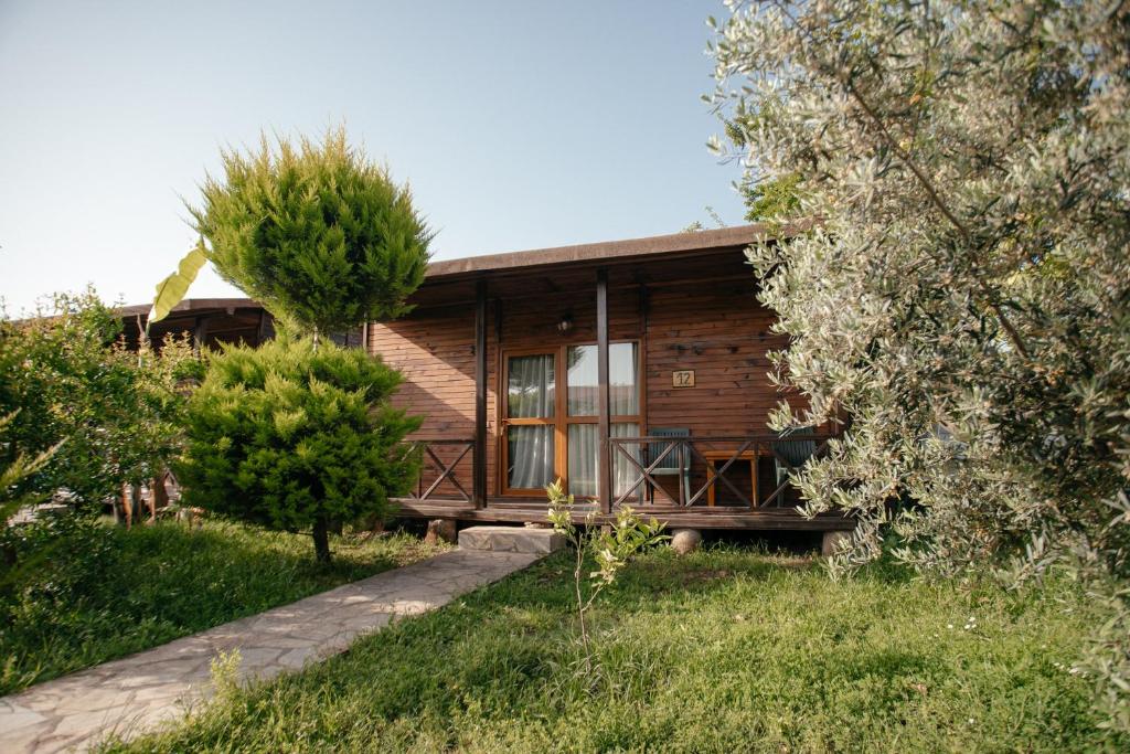 eine Blockhütte mit einer Veranda und Bäumen in der Unterkunft Serenity Bungalows in Cıralı