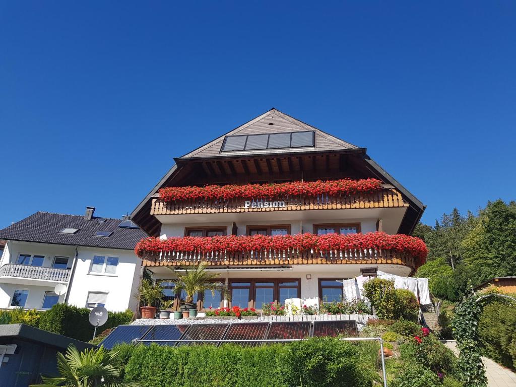 une maison avec des fleurs rouges en haut dans l'établissement Pension Florianhof, à Schonach