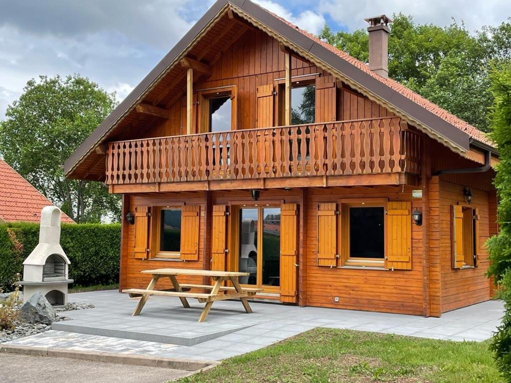 une maison en bois avec une table de pique-nique devant elle dans l'établissement CHALET 6 PERS INDEPENDANT PROCHE CENTRE ET LAC, à Gérardmer