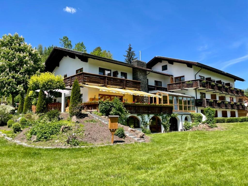 a large house on top of a green field at Gasthof Pension Fischerstüberl in Blaibach