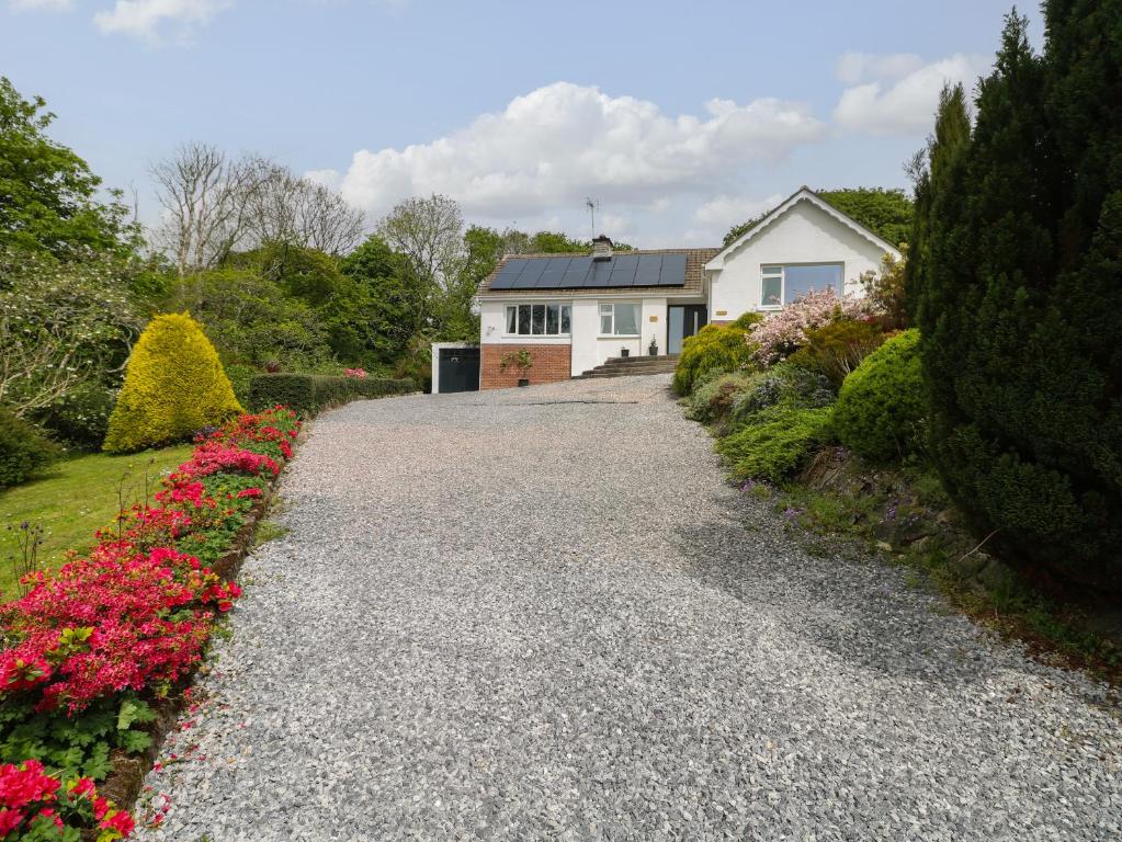 a driveway leading to a white house with flowers at The Dingle in Narberth