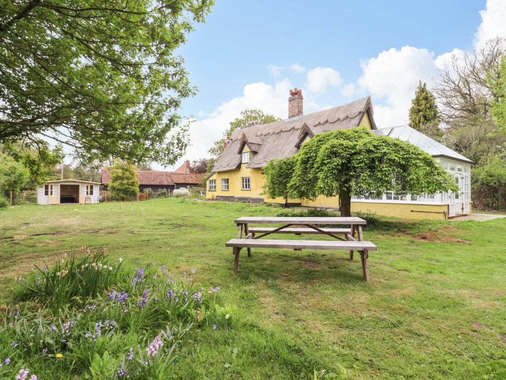 una mesa de picnic en un campo frente a una casa en The Abbey Cottage, en Cockfield