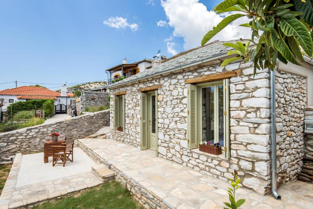 a stone house with a patio and a table at Ahirona in Theologos