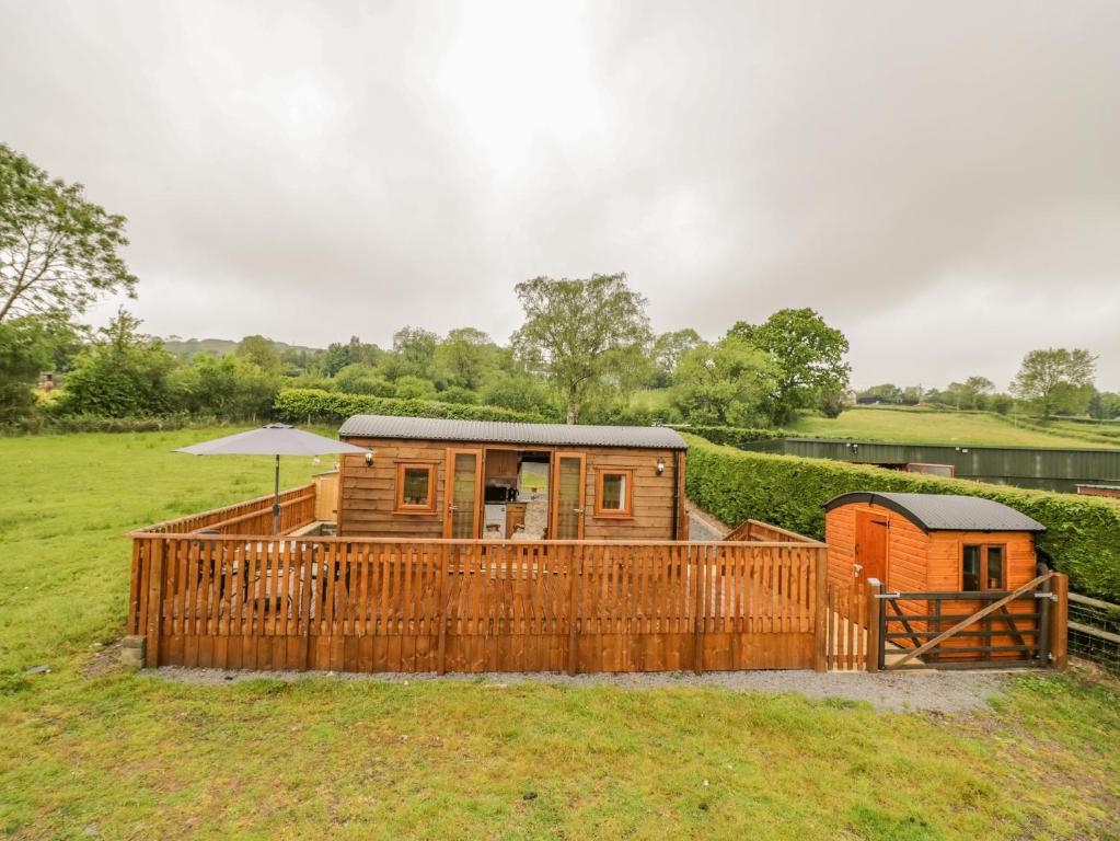 a wooden cabin in a field with an umbrella at Shepherds Retreat in Kidderminster
