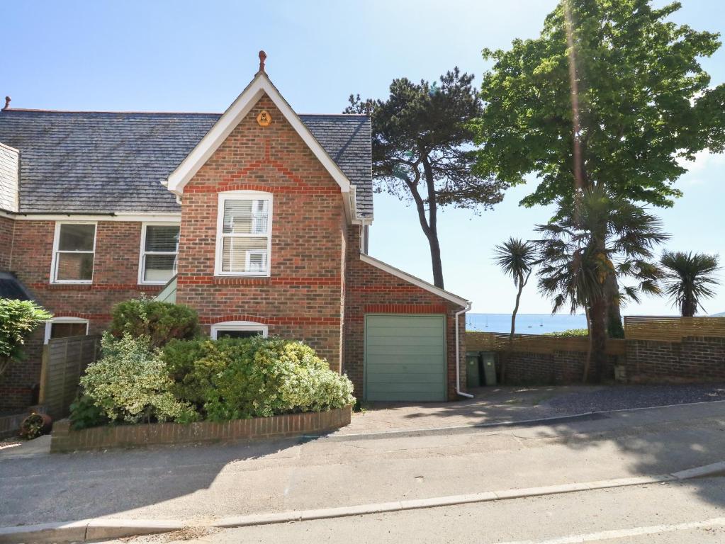 a brick house with a garage in front of the ocean at Castle Cove Cottage in Weymouth