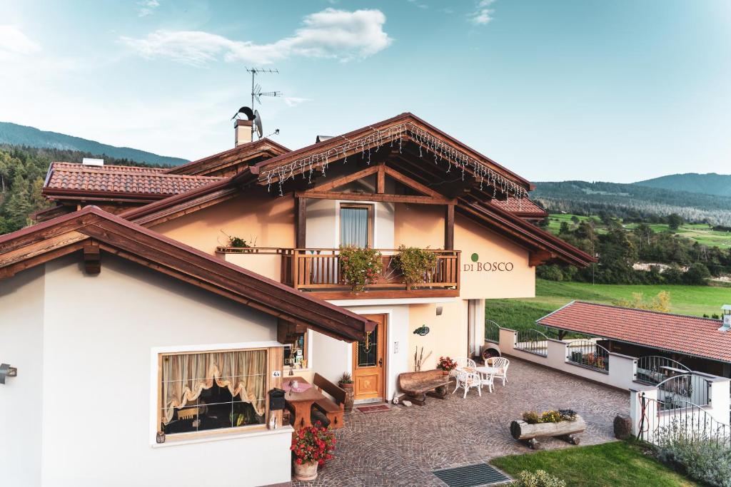 una casa con balcone e persone sedute su un patio di Agritur Bella di Bosco a Coredo