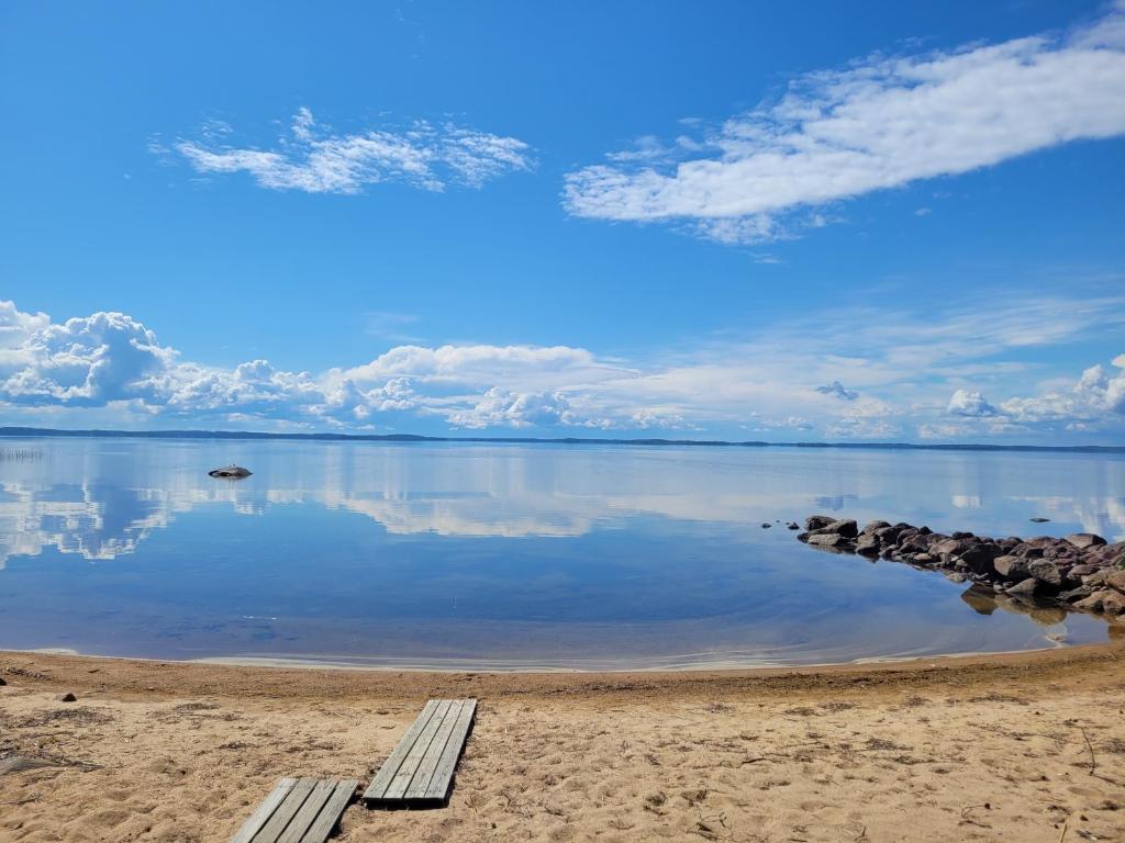 two benches sitting on the beach near the water at Lakeland Karelia Fisherman's Paradise in Kesälahti