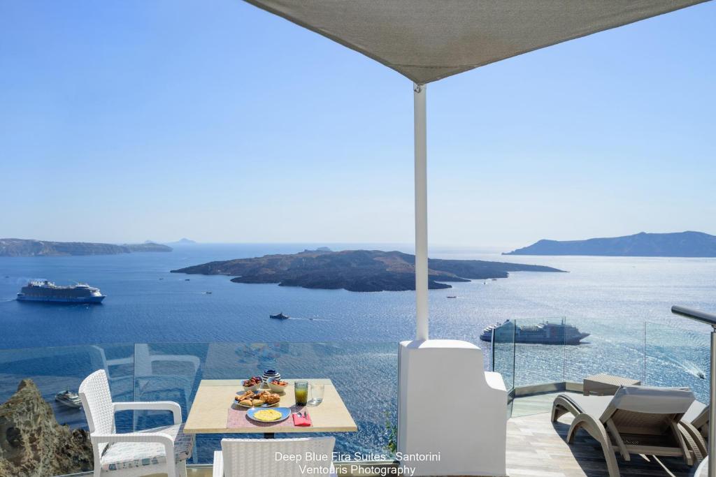 a table and chairs with a view of the ocean at Fira Deep Blue Suites in Fira