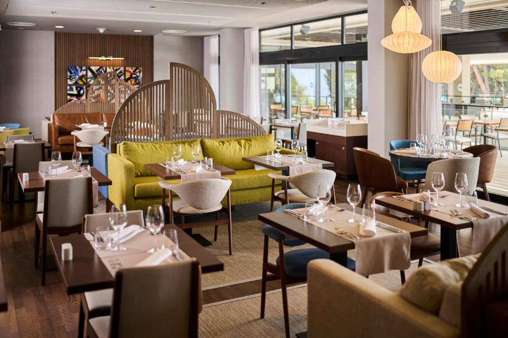 a restaurant with tables and yellow chairs and tablesktop at Hotel Parentium Plava Laguna in Poreč