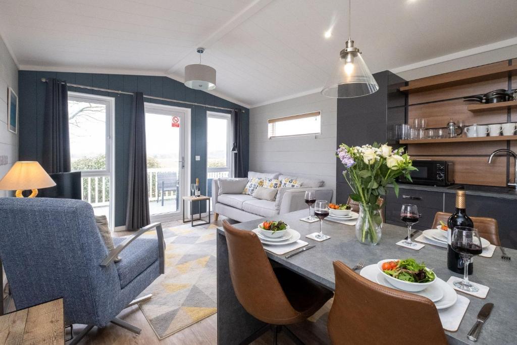 a kitchen and living room with a table and chairs at Savannah Lodge - Aldeburgh Coastal Cottages in Sizewell