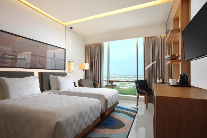 a hotel room with two beds and a desk at Resinda Hotel Karawang in Karawang