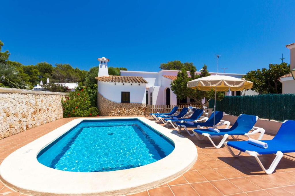 a swimming pool with chairs and an umbrella at Villa Casa Blanca by Villa Plus in Cala Blanca