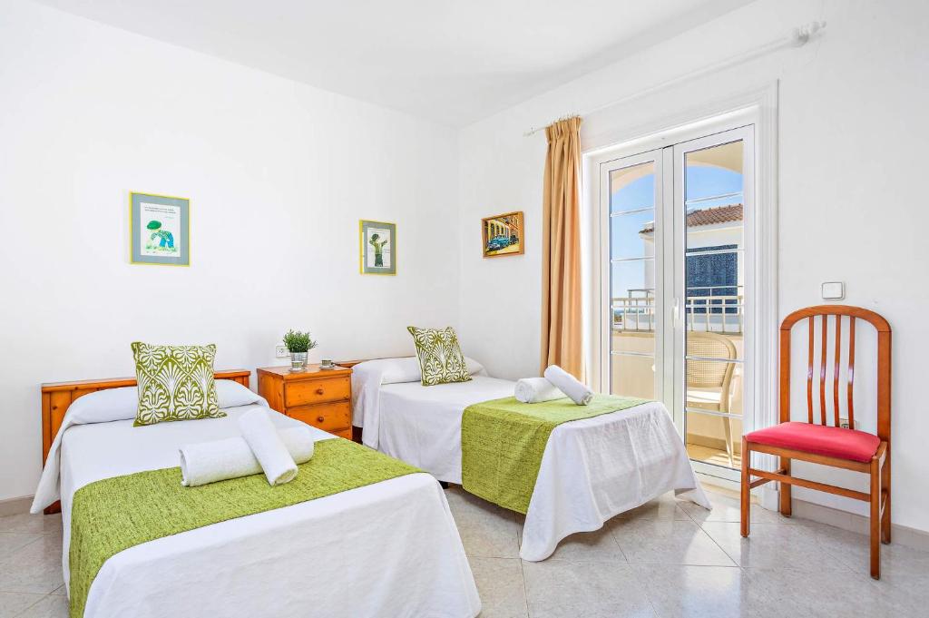 pokój z dwoma łóżkami, krzesłem i oknem w obiekcie Villa Sunflower by Villa Plus w mieście Cala Blanca
