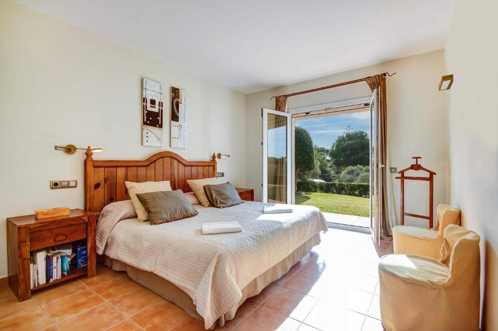 um quarto com uma cama, uma cadeira e uma janela em Villa Tama by Villa Plus em Sant Lluis