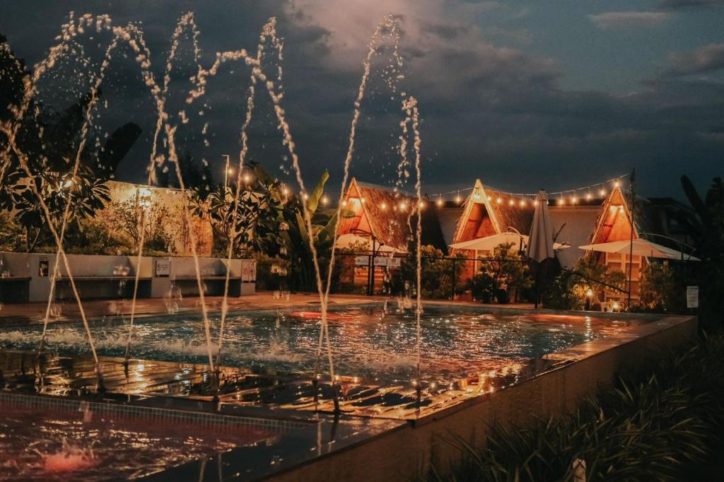 - une fontaine au milieu d'une piscine la nuit dans l'établissement Urban Oasis Resort, Tarlac, à Tarlac