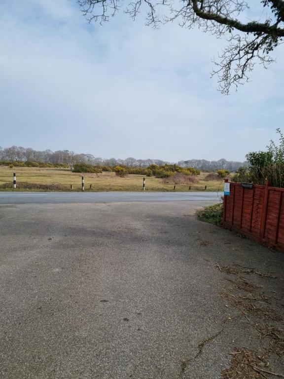 an empty road with a fence on the side of the road at Lovely 2-Bedroom New Forest apartment on a Farm in New Milton