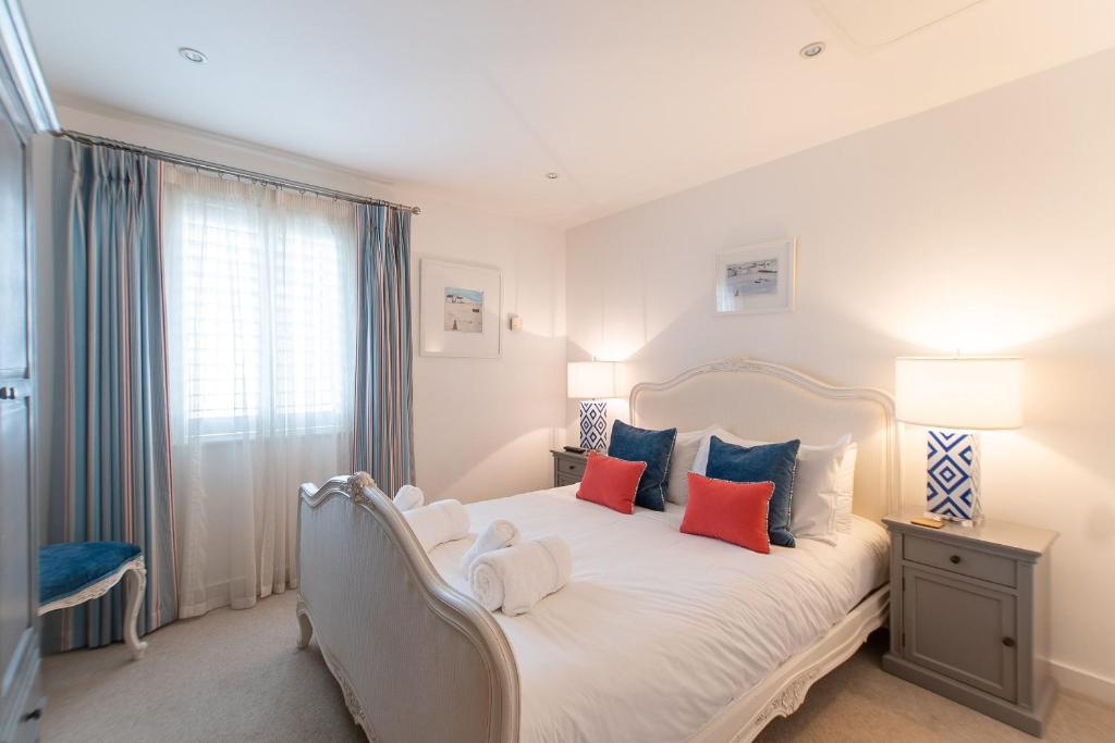 a bedroom with a white bed with blue and red pillows at Wingtips in Carbis Bay