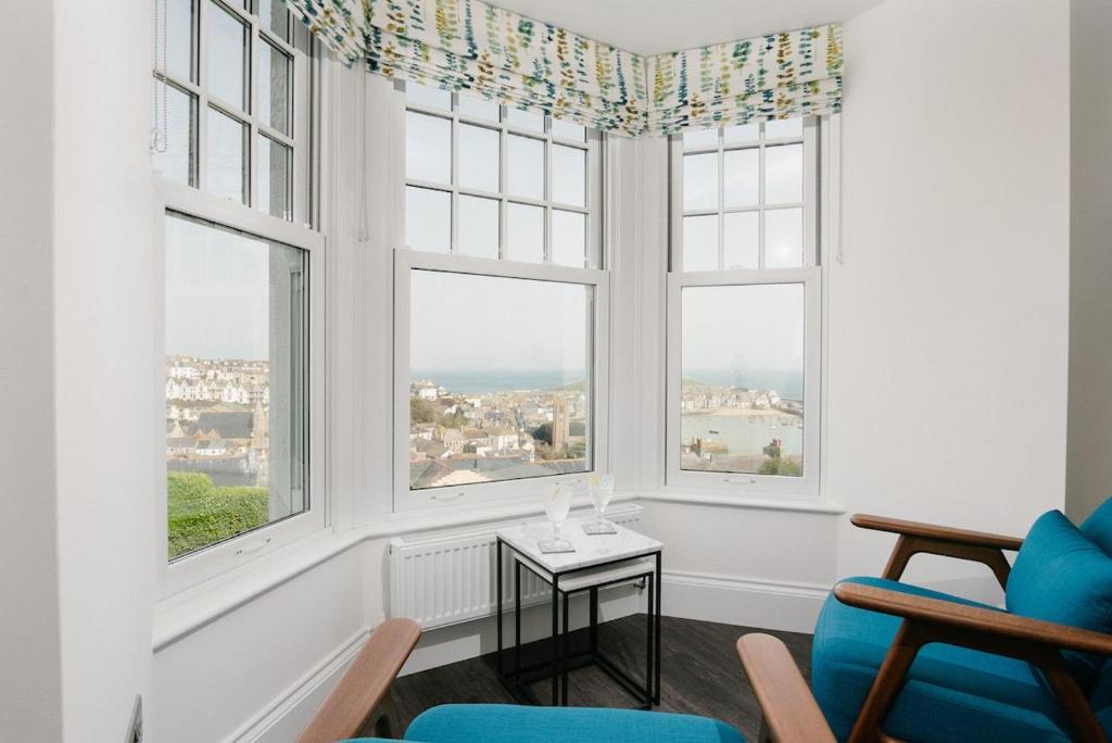 uma sala de estar com janelas e uma mesa e cadeiras em Harbour Vista em St. Ives