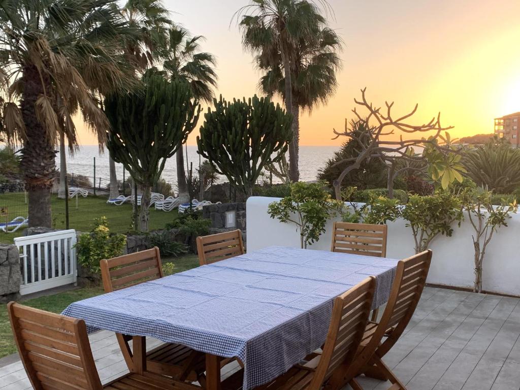 einen Tisch und Stühle auf einer Terrasse mit Meerblick in der Unterkunft Prime Homes- San Miguel Golf,Ocean Front Bungalow in San Miguel de Abona