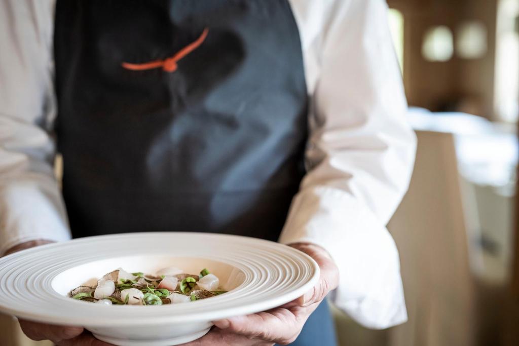 a person holding a white plate with food on it at Adler Spa Resort Dolomiti in Ortisei