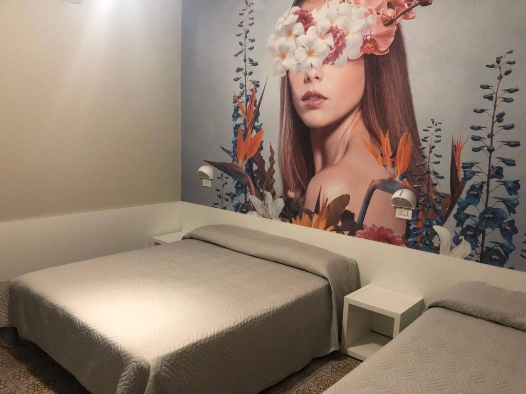 ベッラーリア・イジェア・マリーナにあるHotel Wegaの花の壁に女性の壁画が施されたベッドルーム