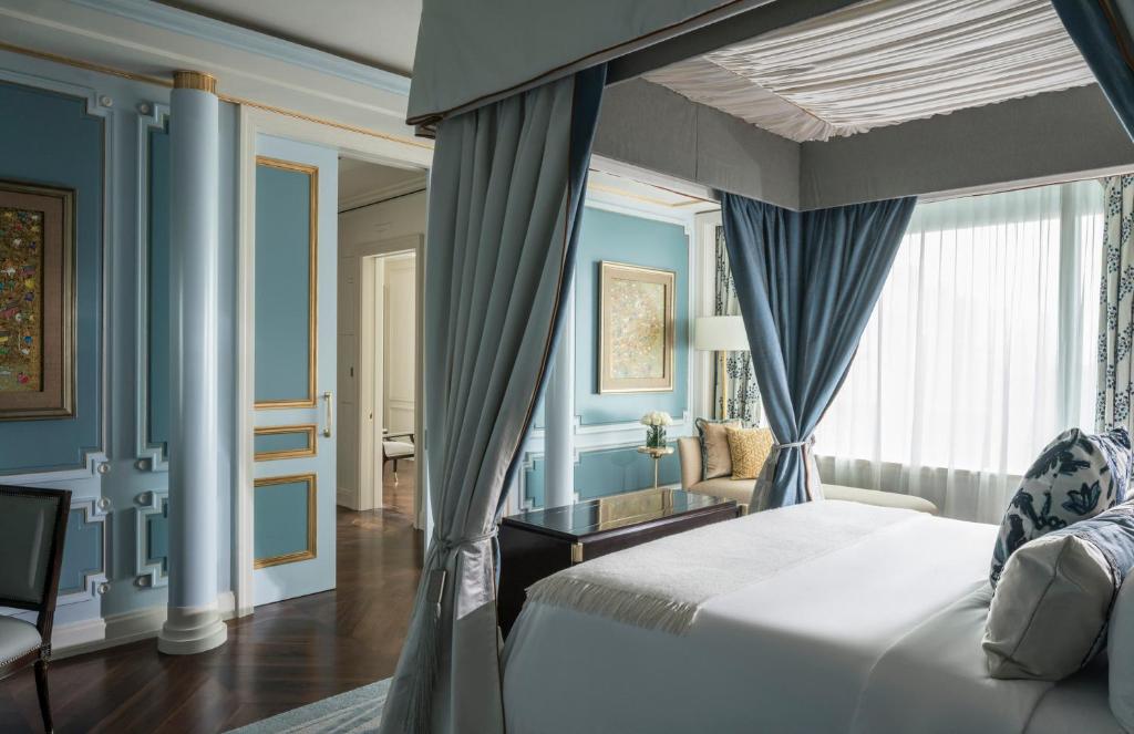 1 dormitorio con paredes azules, 1 cama y ventana en Four Seasons Hotel Jakarta, en Yakarta