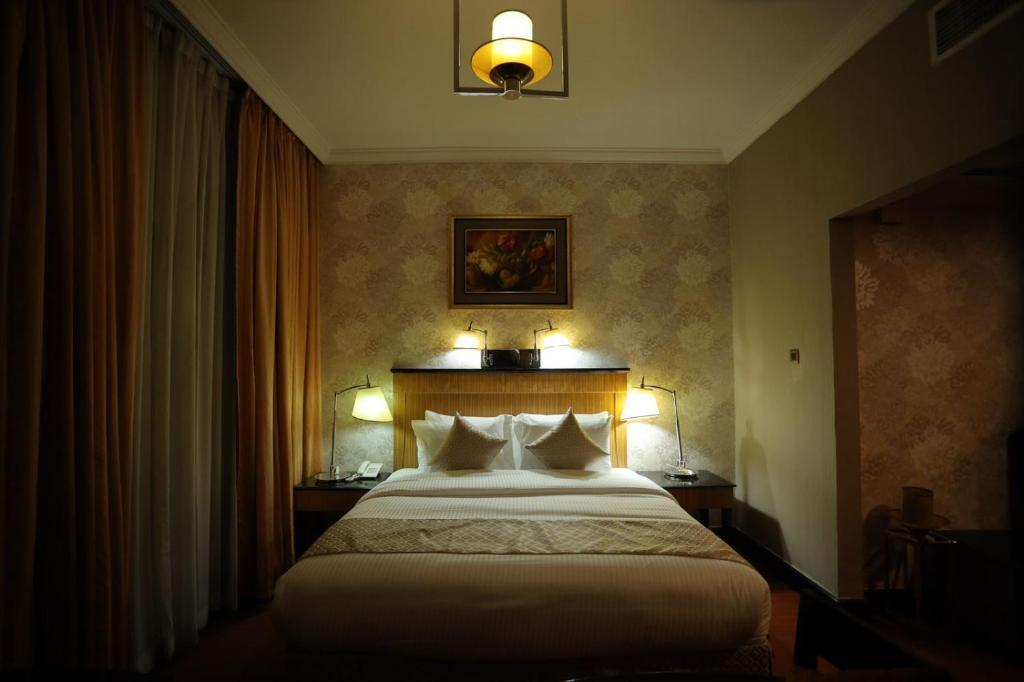 - une chambre d'hôtel avec un lit et deux lampes dans l'établissement CREEK GATE HOTEL-BAITHANS, à Charjah