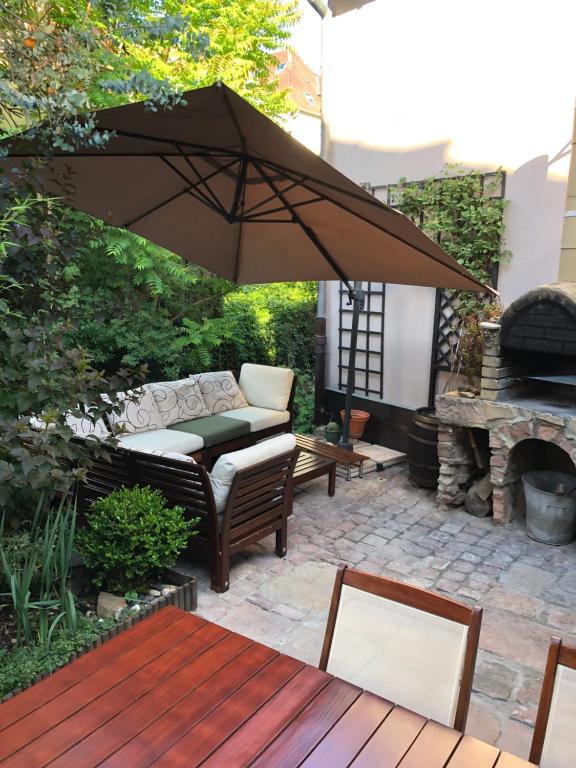 une terrasse avec un parasol, un canapé et une cheminée dans l'établissement Le gîte du Moulin, à Colmar