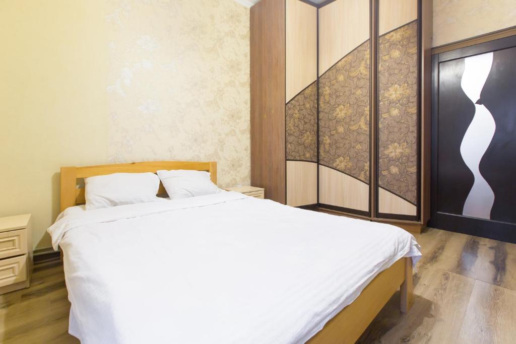 リヴィウにあるКвартира подобово біля Площі Ринок вулиця Староєврейська 17の白いベッドと壁に絵画が飾られたベッドルーム1室