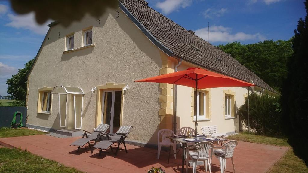 a table and chairs with a red umbrella in front of a house at Ferienwohnung am Gutshaus Pamitz in Klein Bünzow