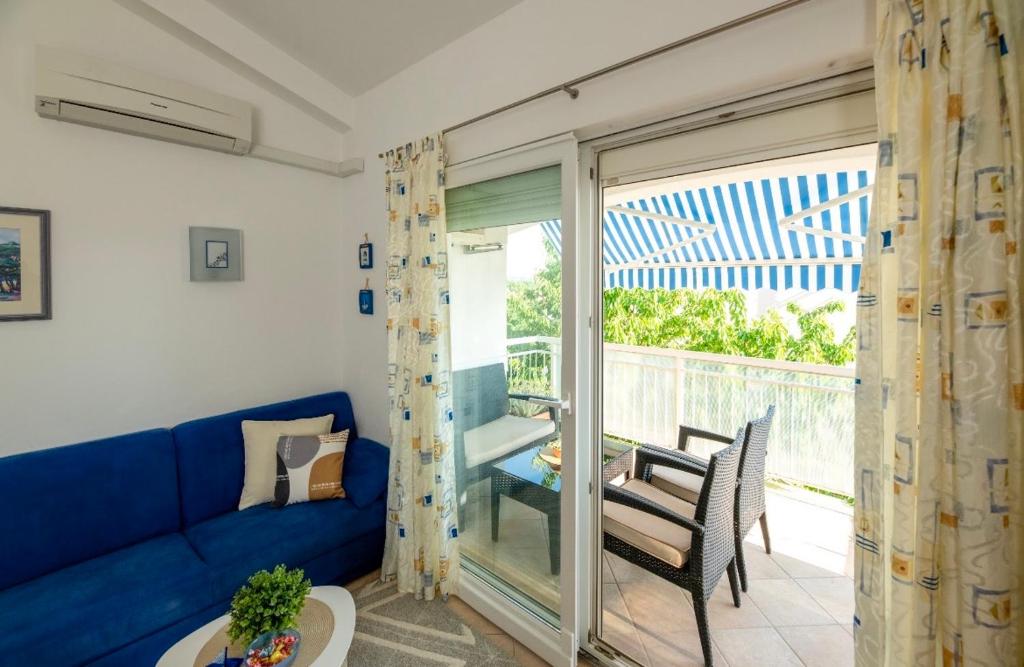 a living room with a blue couch and a balcony at Sisi Apartment in Vabriga
