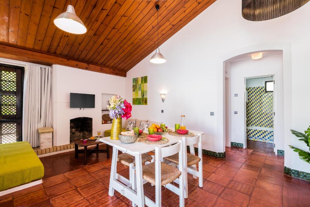 een woonkamer met een witte tafel en een gele bank bij Casas Barulho - Villa Jacaranda A8 in Albufeira