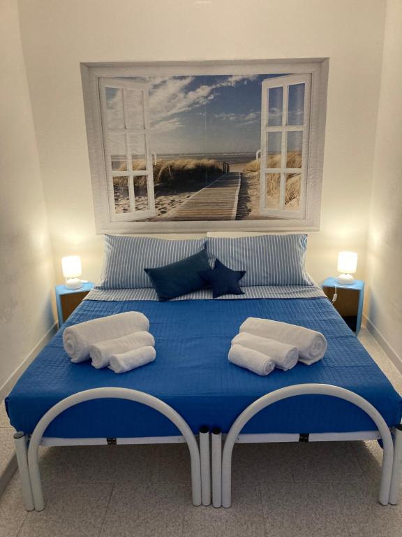 a bedroom with a blue bed with a painting on the wall at Casa Vacanze Casti - 41 in Calasetta